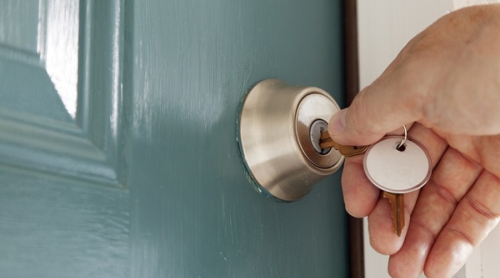 Man turning the key on the front door lock